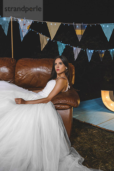 Seriöse Braut liegt auf dem Sofa auf einer Nachtfeld-Party