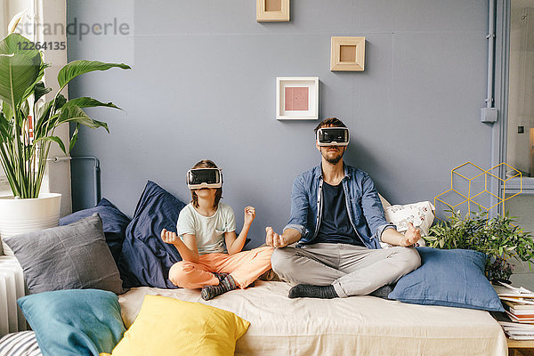 Vater und Sohn mit VR-Brille beim Yoga zu Hause
