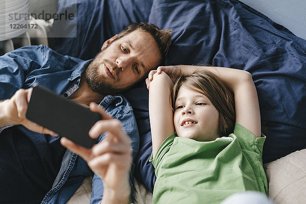 Vater und Sohn schauen gemeinsam zu Hause auf das Smartphone