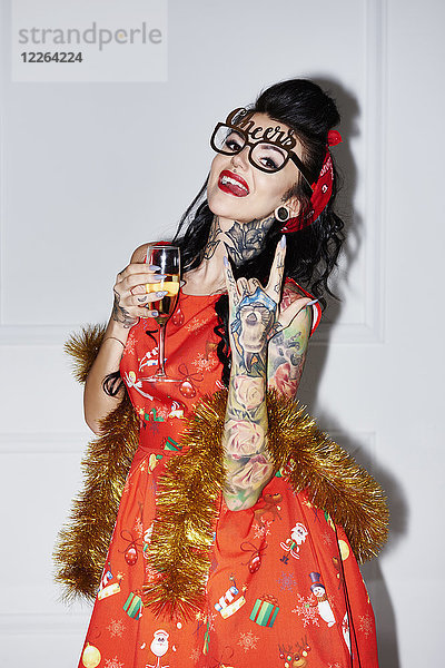 Portrait einer tätowierten Frau mit Champagnerglas mit Rock And Roll Schild