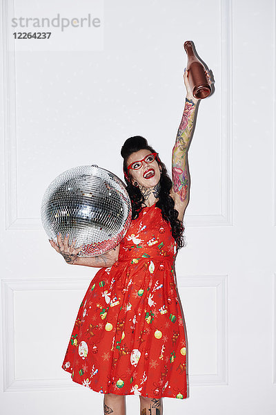 Portrait einer tätowierten Frau mit Champagnerflasche und Discokugel