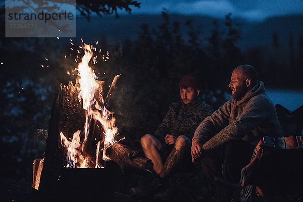 Kanada  British Columbia  zwei Männer sitzen nachts am Lagerfeuer am Boya Lake.