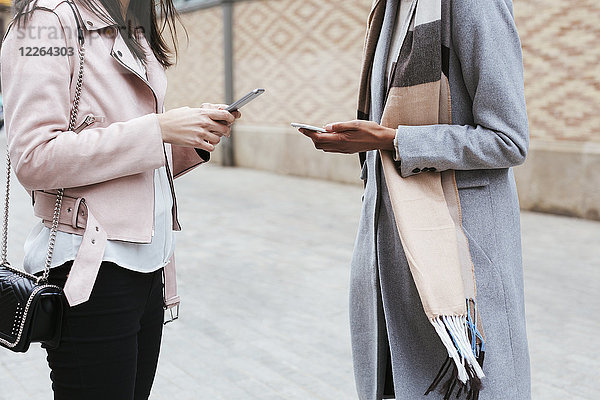 Nahaufnahme von zwei Frauen  die Mobiltelefone in der Stadt benutzen