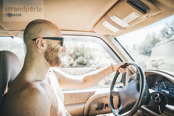 Barechested glücklich junger Mann mit Sonnenbrille und Bart auf einem Roadtrip