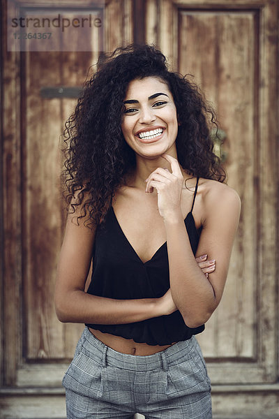 Porträt einer lachenden jungen Frau mit lockigem Haar