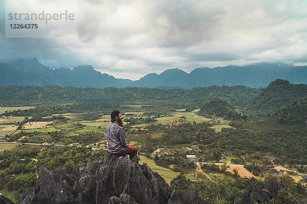 Laos  Vang Vieng  Wanderer auf dem Felsen sitzend  Blick in die Ferne