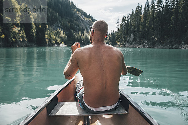 Kanada  British Columbia  nackter Mann im Kanu auf dem Kinbasket Lake