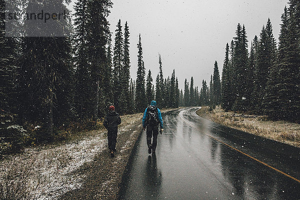 Kanada  British Columbia  Yoho Nationalpark  zwei Männer beim Wandern auf der Yoho Valley Road bei Schneefall