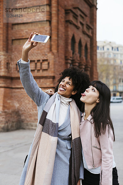 Spanien  Barcelona  zwei verspielte Frauen  die einen Selfie an einem Tor nehmen.