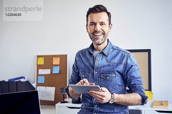 Porträt eines lächelnden Mannes mit Tablette im Büro