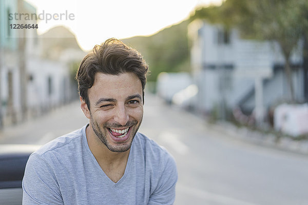 Porträt eines lachenden jungen Mannes mit lustigen Gesichtern