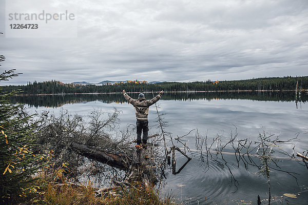 Kanada  British Columbia  Mann steht am Blue Lake und hebt seine Arme.