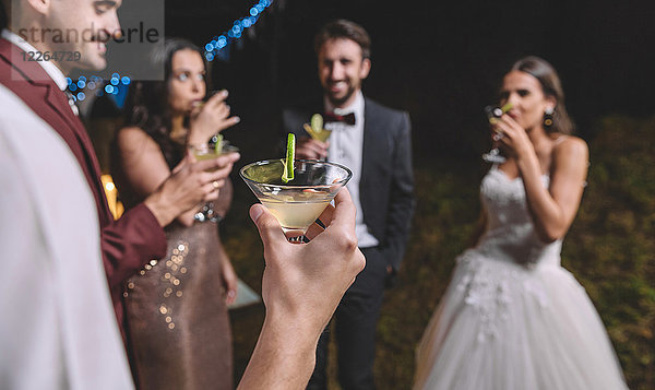 Fröhliche Freunde trinken Cocktails auf einer Nachtfeldhochzeitsparty