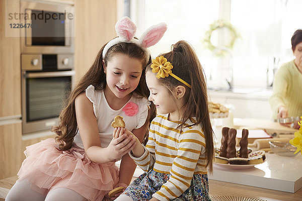 Zwei Mädchen  die sich in der Küche einen Keks ansehen.