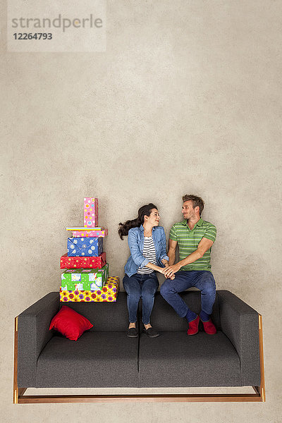Glückliches Paar sitzend auf der Couch mit vielen Geschenken