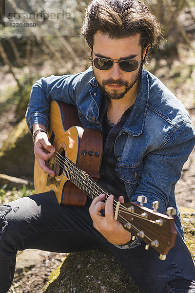 Junger Mann spielt Gitarre im Freien