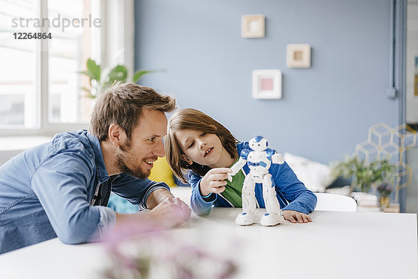 Glücklicher Vater und Sohn beim Spielen mit dem Roboter auf dem Tisch zu Hause
