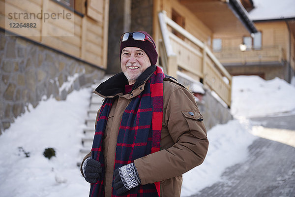 Porträt eines lächelnden älteren Mannes im Bergdorf im Winter