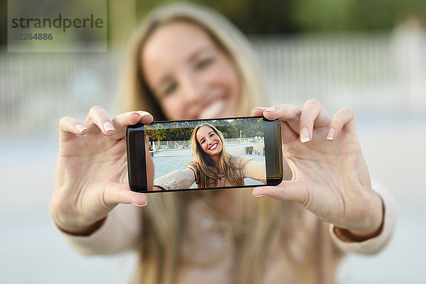Glückliche junge Frau nimmt Selfie mit Handy  Nahaufnahme