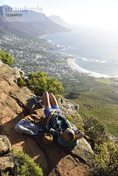 Südafrika  Kapstadt  Frau auf dem Felsen liegend während der Wanderung zum Lion's Head