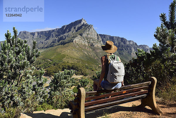 Südafrika  Kapstadt  Frau sitzend auf der Bank beim Wanderausflug zum Löwenkopf