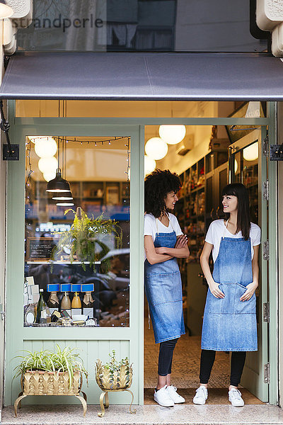 Zwei lächelnde Frauen stehen in der Eingangstür eines Ladens.