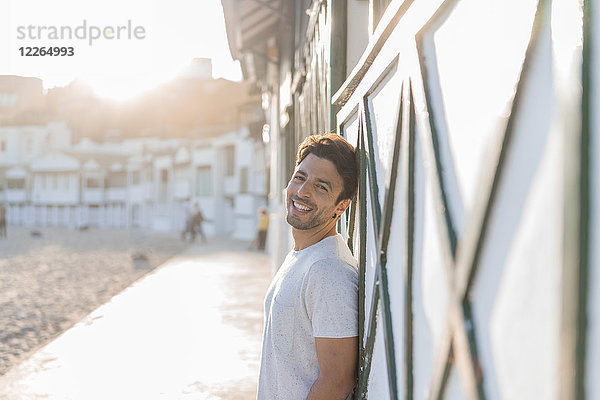 Porträt eines glücklichen jungen Mannes am Strand bei Sonnenuntergang