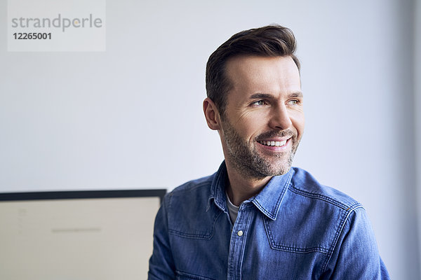 Porträt eines lächelnden Mannes im Büro mit seitlichem Blick
