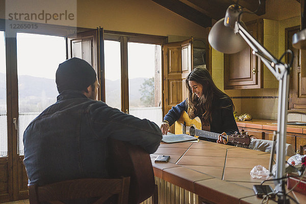 Junges Paar spielt Gitarre zu Hause am Tisch