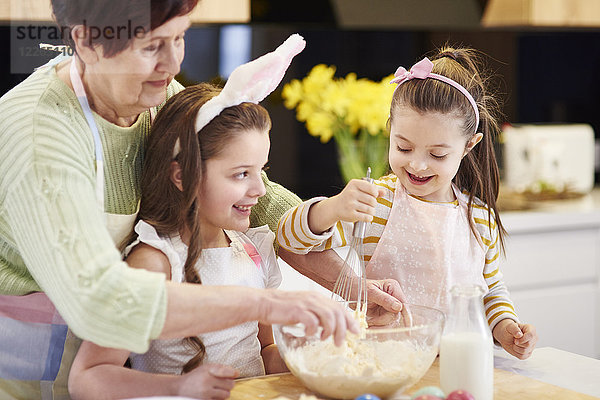 Großmutter und Enkelinnen backen gemeinsam Osterkekse in der Küche