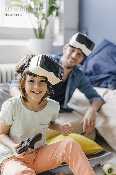 Porträt eines glücklichen Jungen und Vaters mit VR-Brille beim Videospiel zu Hause