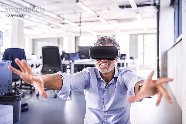 Glücklicher reifer Geschäftsmann mit VR-Brille im Büro