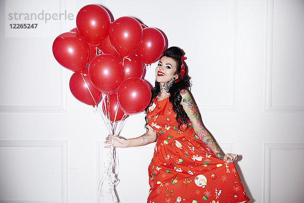 Portrait einer tätowierten Frau mit roten Luftballons