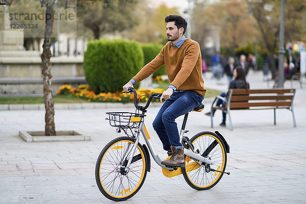 Junger Mann auf dem Leihfahrrad in der Stadt