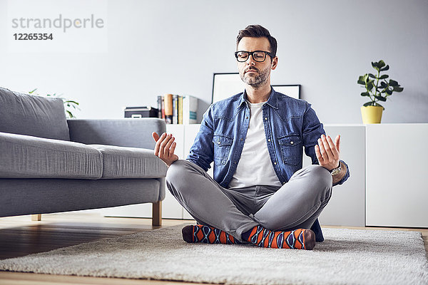 Entspannter Mann beim Meditieren zu Hause