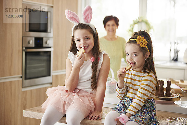 Porträt von zwei lächelnden Mädchen  die in der Küche Kekse essen