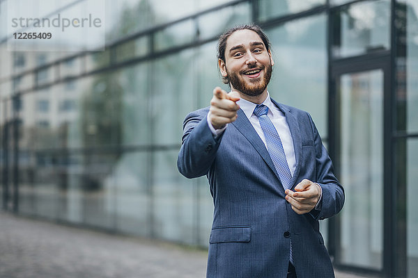 Porträt eines glücklichen Geschäftsmannes  der mit dem Finger nach draußen zeigt.