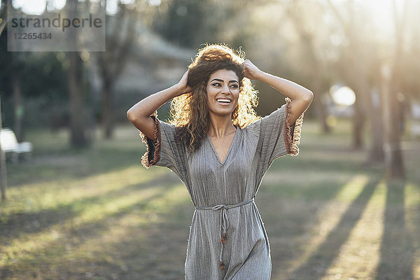 Porträt einer glücklichen jungen Frau im Park bei Gegenlicht