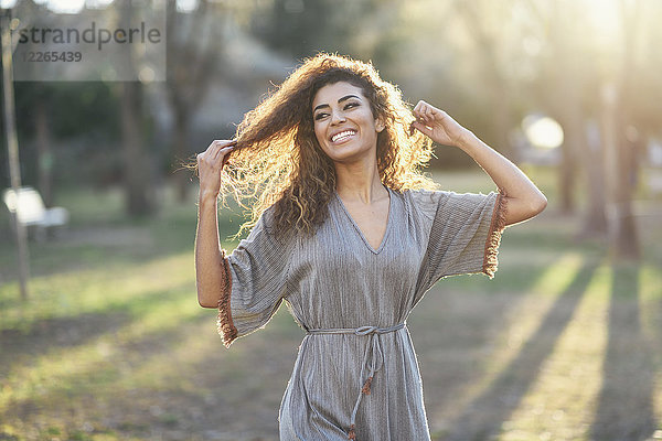 Porträt einer glücklichen jungen Frau im Park bei Gegenlicht