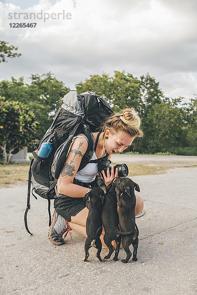 Kuba  junge Frau mit Rucksack streichelt junge Hunde  lachend