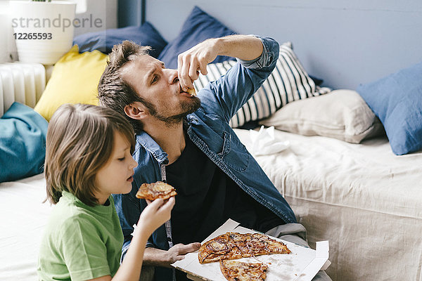 Vater und Sohn essen Pizza zu Hause