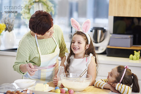 Großmutter und Enkelinnen backen gemeinsam Osterkekse in der Küche