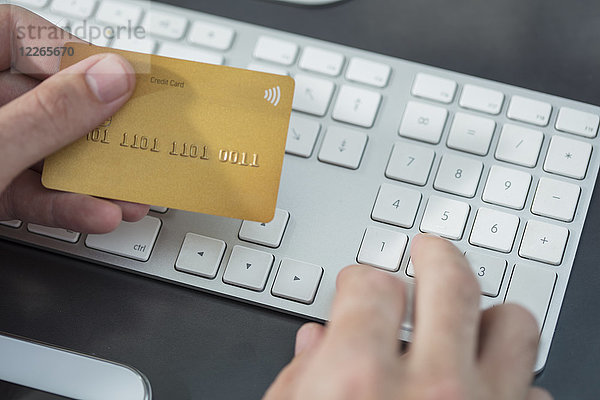 Mann bei der Online-Zahlung mit Kreditkarte am Schreibtisch  Nahaufnahme