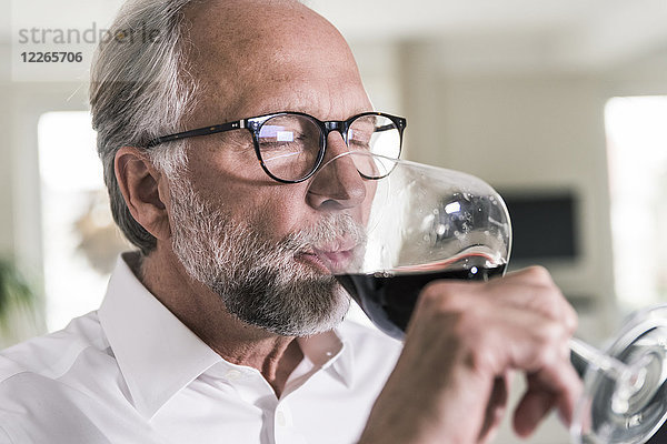 Porträt eines reifen Mannes  der ein Glas Rotwein trinkt.