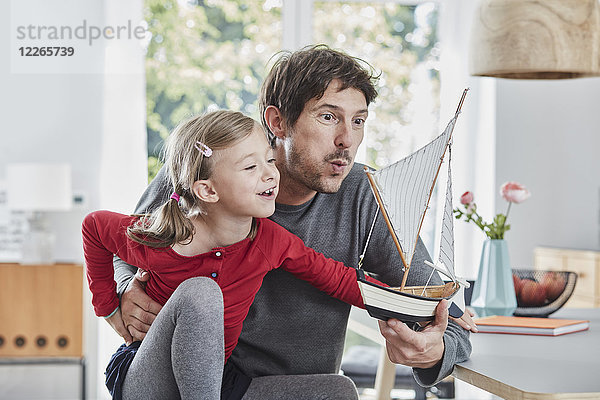 Glücklicher Vater und Tochter beim Spielen mit dem Modellboot zu Hause