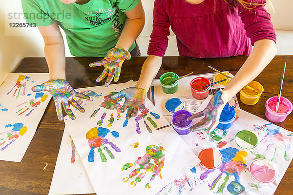 Mädchen und Junge spielen mit Fingerfarbe  Handabdrücke