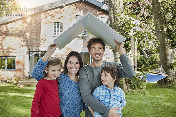Porträt einer glücklichen Familie im Garten ihres Hausdaches