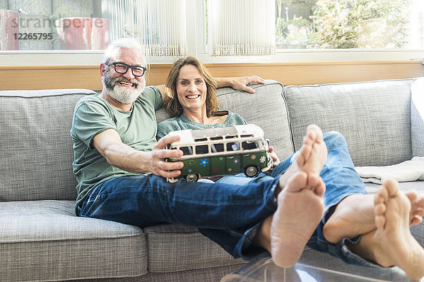 Glückliches reifes Paar auf der Couch zu Hause mit Minibusmodell