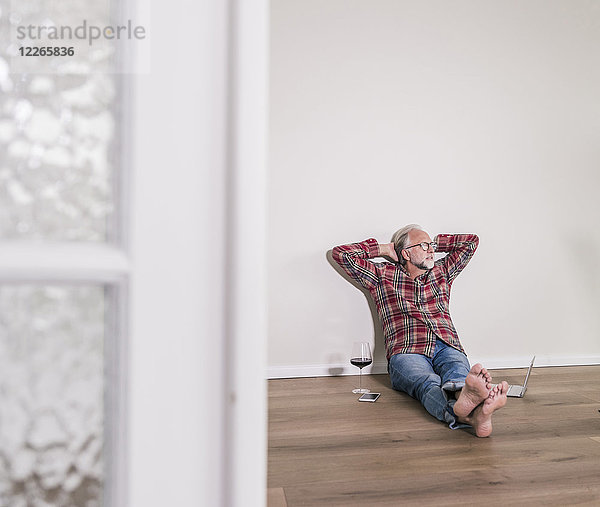 Barfuss-Mann entspannt auf dem Boden zu Hause