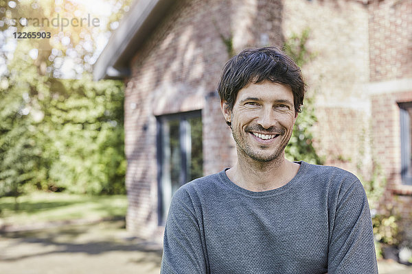 Porträt eines lächelnden Mannes vor seinem Haus